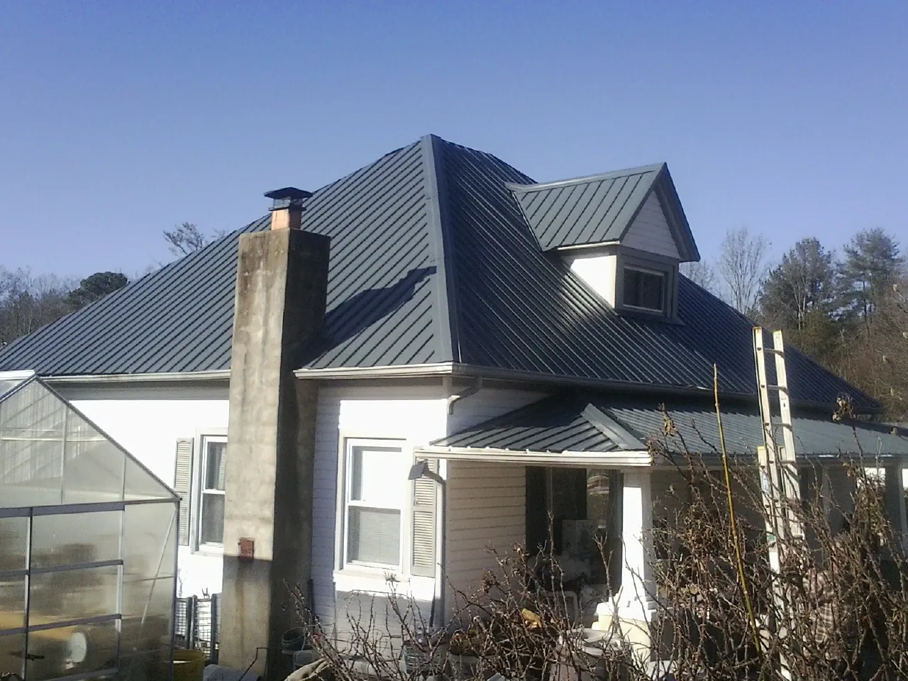 Dark blue standing seam metal roof on a white farmhouse with dormer — Slate & Tile Roof Repair by Roofing Brothers in Jemez Pueblo