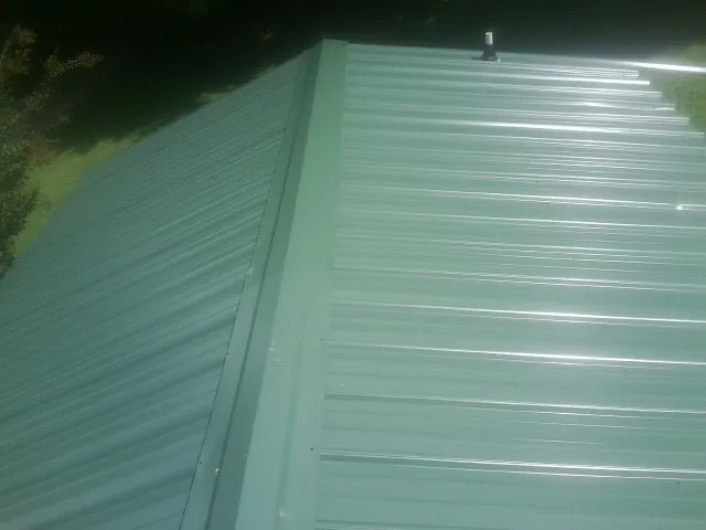 New green metal panels meeting at the ridge of a roof — Flat Roof Repair work by our crew in Jemez Pueblo