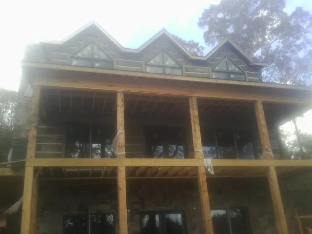 Dormers and porch framing on a large log home under construction — Roof Coating work by our crew in Jemez Pueblo