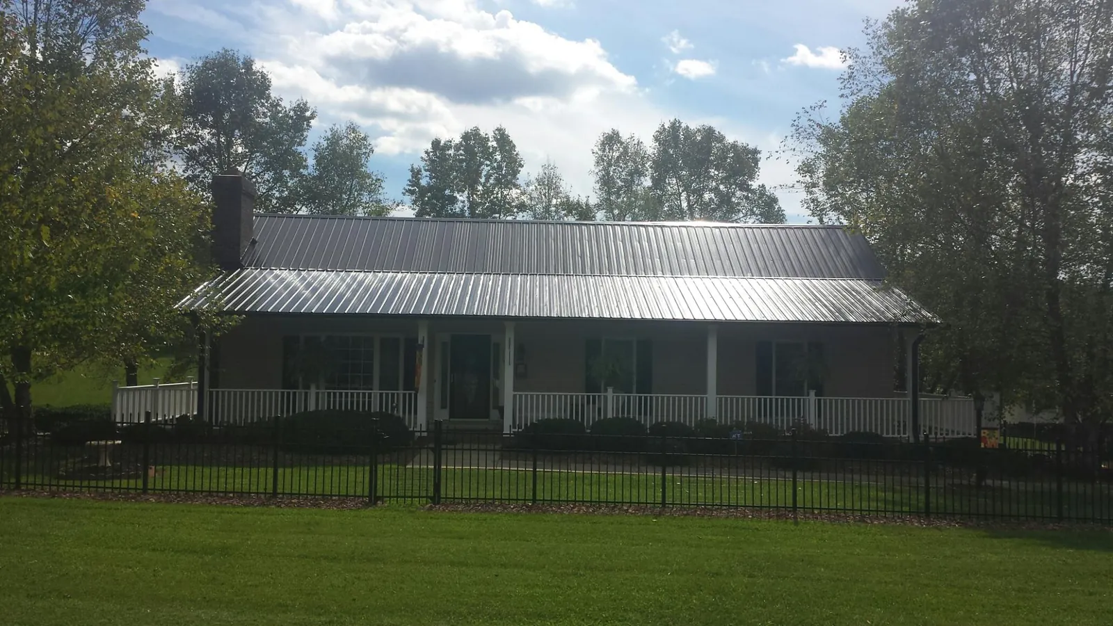 Gray metal roof on a brick ranch with a full width front porch — Gutter Guard Installation work by our crew in Jemez Pueblo