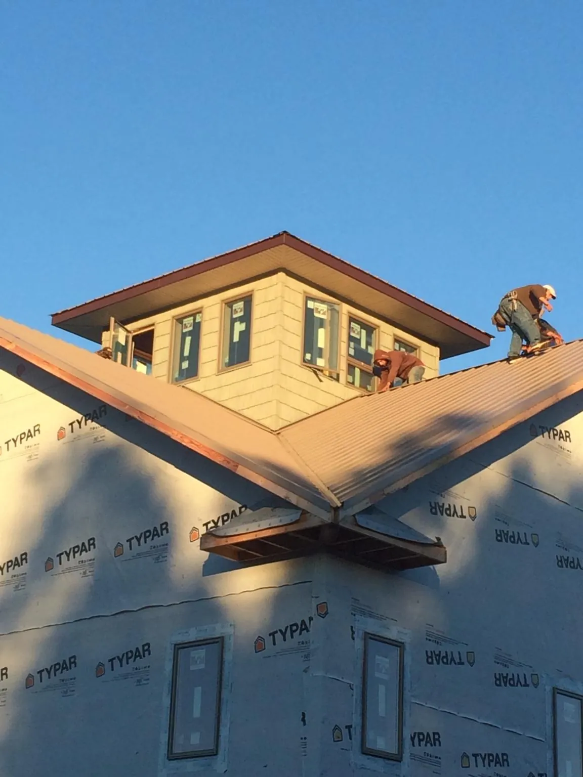 Roofers working around a rooftop cupola on a new metal roof at sunset — Roof Waterproofing in Jemez Pueblo by Roofing Brothers